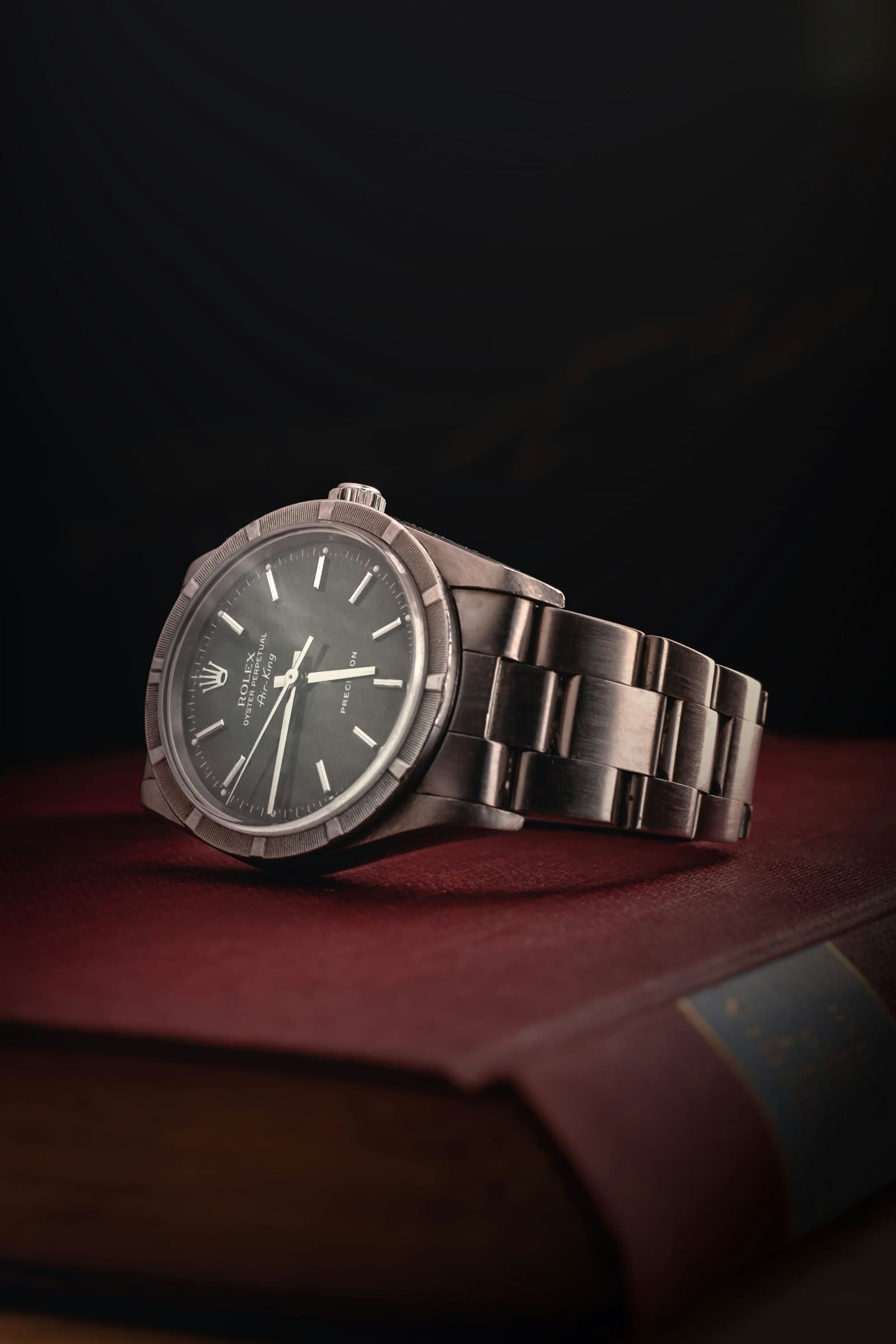A steel Rolex resting on a leather-bound book